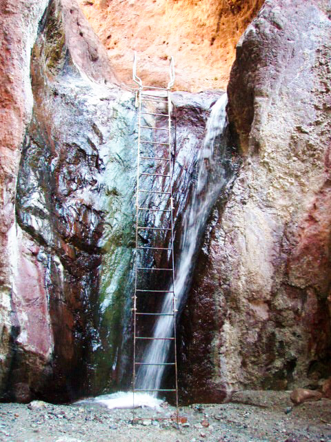 Ladder leaning against rocks and small waterfall