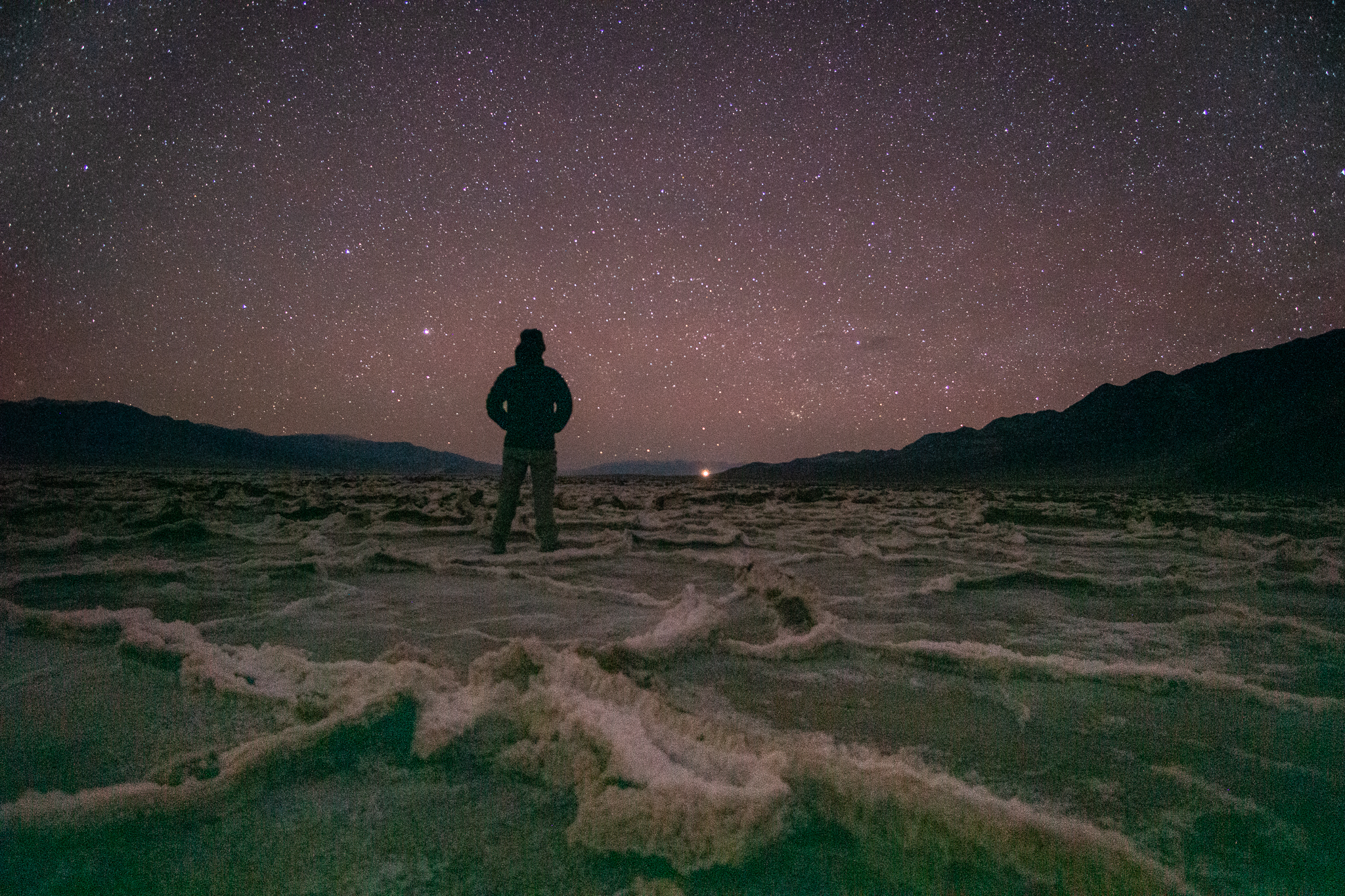 Man in the desert viewing the pink starry almost night sky.