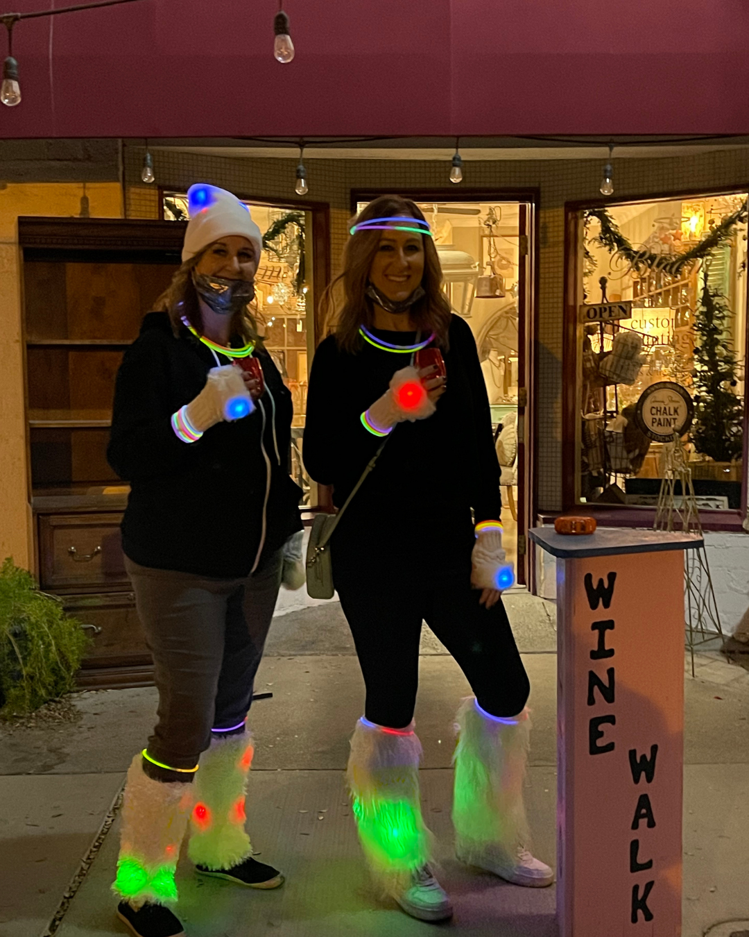 Two women getting giddy and into the theme with glowing white furry boots, hats and gloves.
