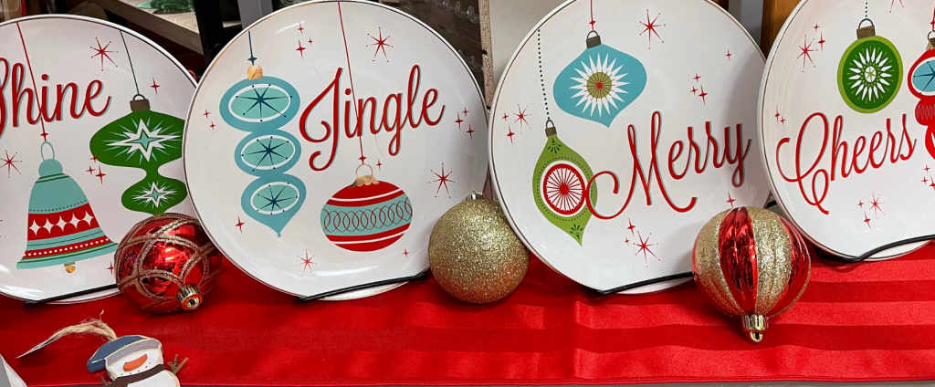 Four holiday plates each with a word: Shine, Jingle, Merry, Cheers
