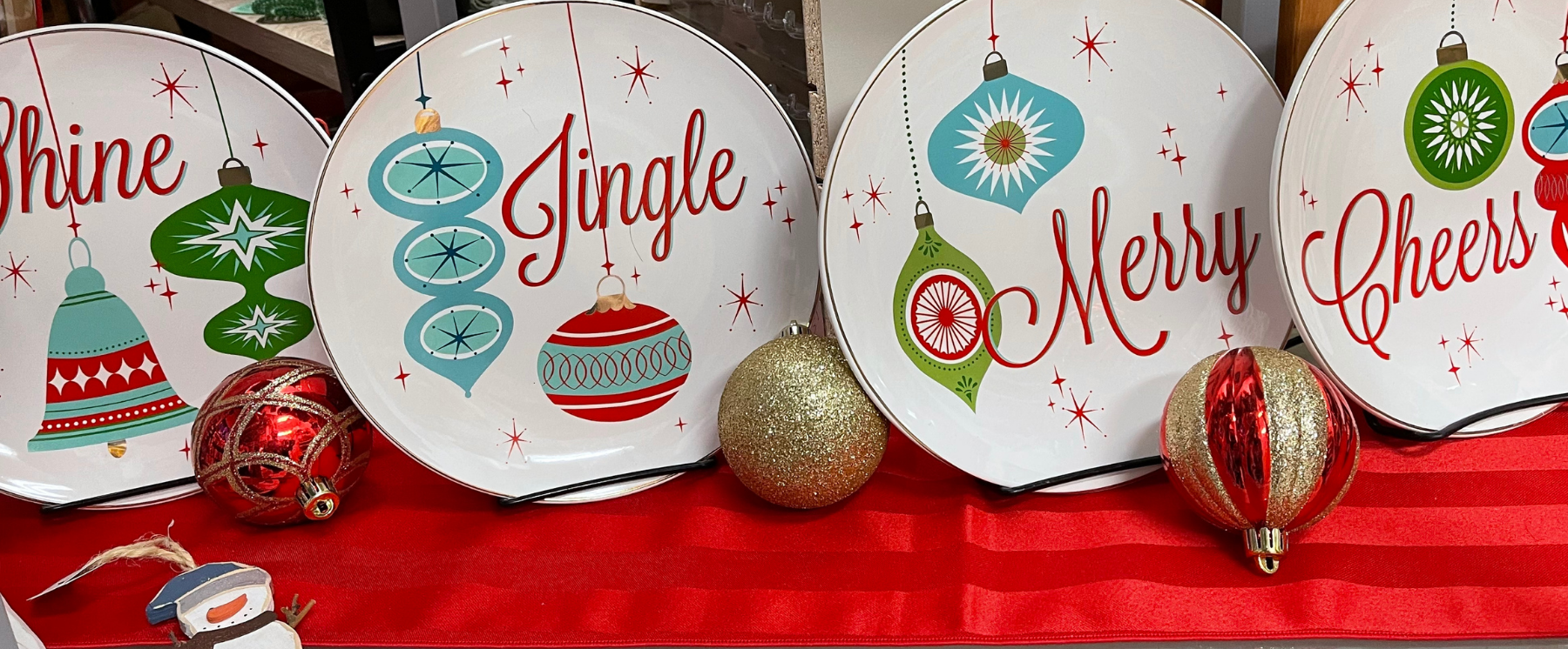 Four holiday plates each with a word: Shine, Jingle, Merry, Cheers