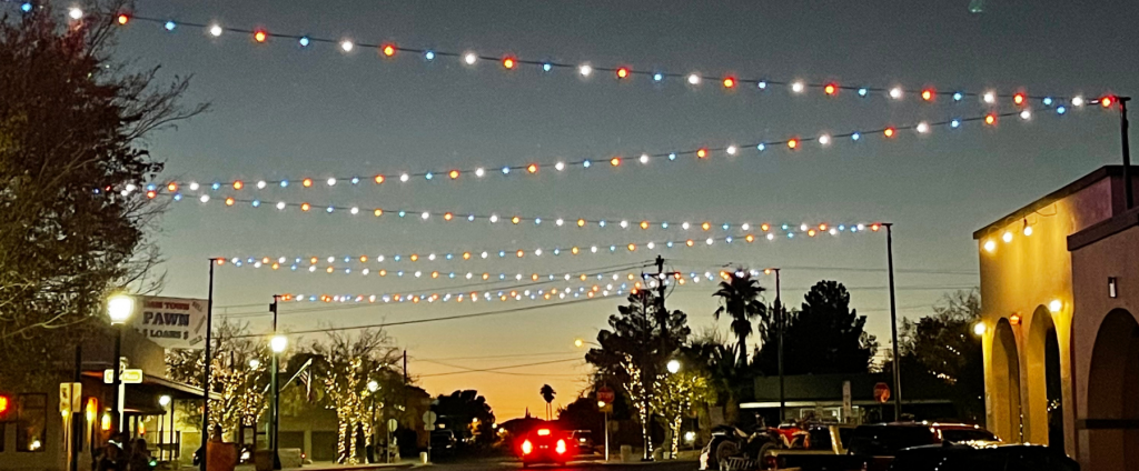 Boulder City Nevada at dusk with holiday lights strung aross the road an car taillights leaving