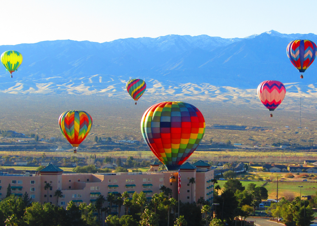 Mesquite Balloon Festival with 6 hot air balloons floating on a sunny with a mountain backdrop