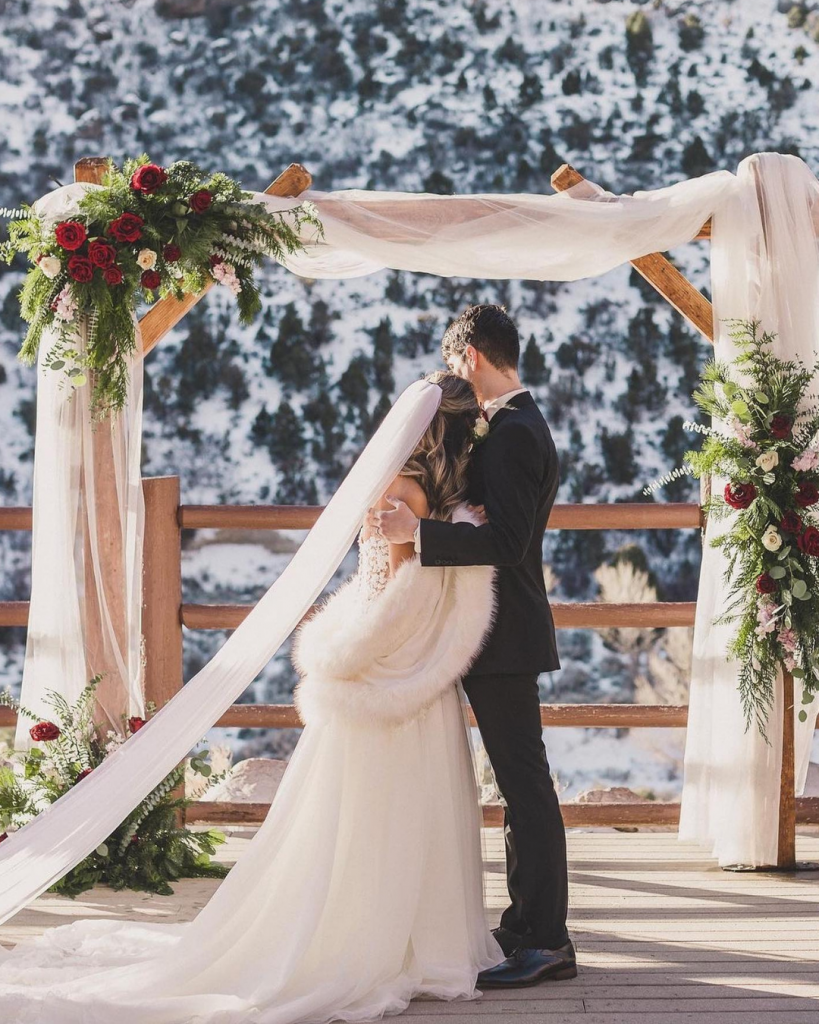 A couple hugging at the alter starring at snow capped mountain