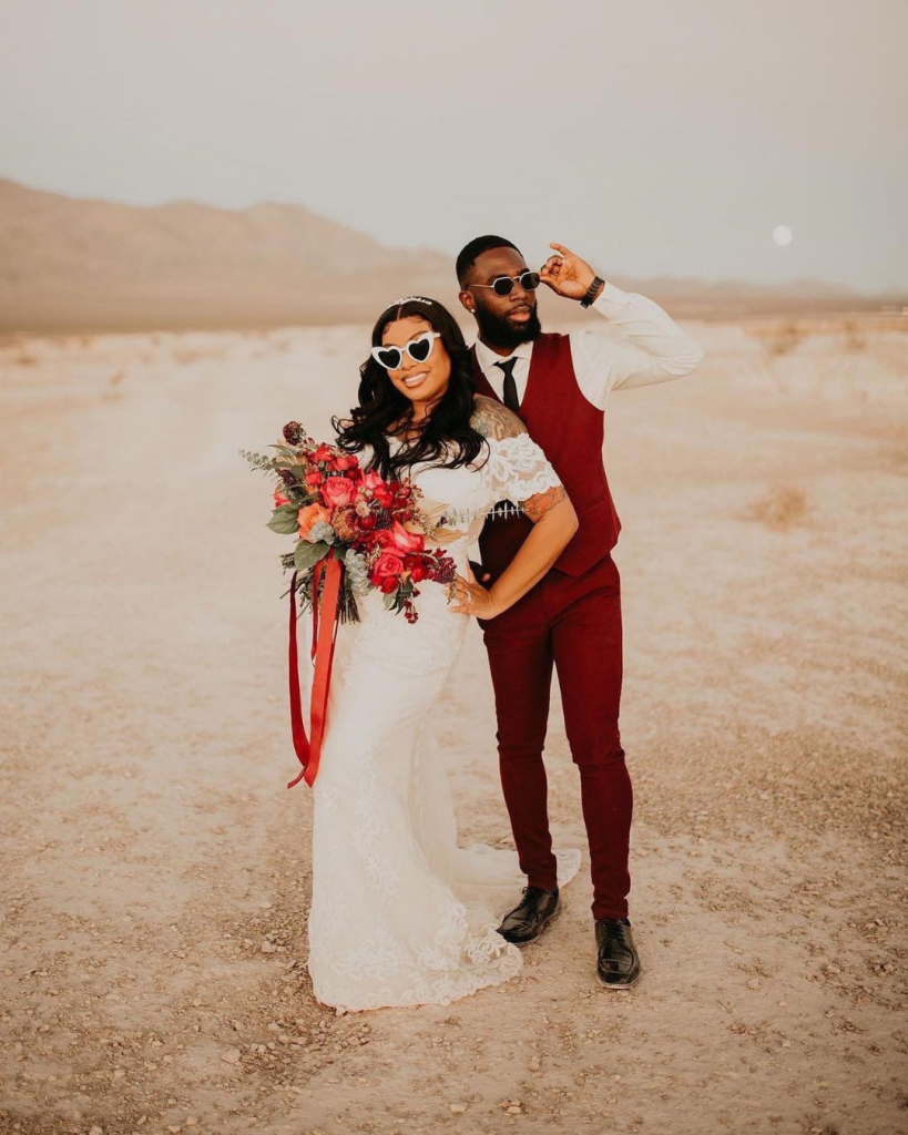 A couple posing in a dusty desert area just outside Las Vegas flanked by mountains and moon rise in background