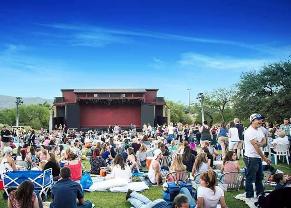 Super summer theatre crowds sit on the lawn with a beautiful light and dark blue sky