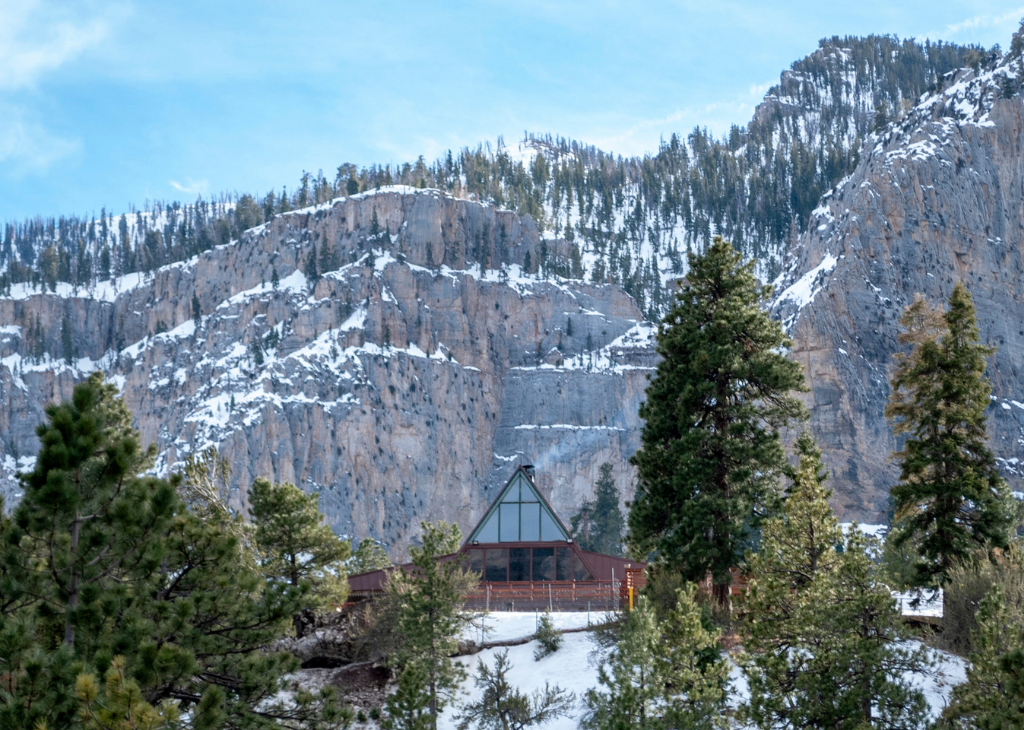 Mount Charleston lodge prior to the fire surrounded by green trees an snow capped mountains