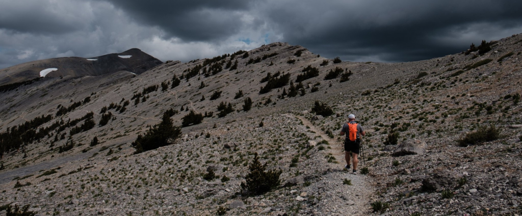 Trent with an orange back pack takes a hike to Mount Charleston's peak on very cloudy day.