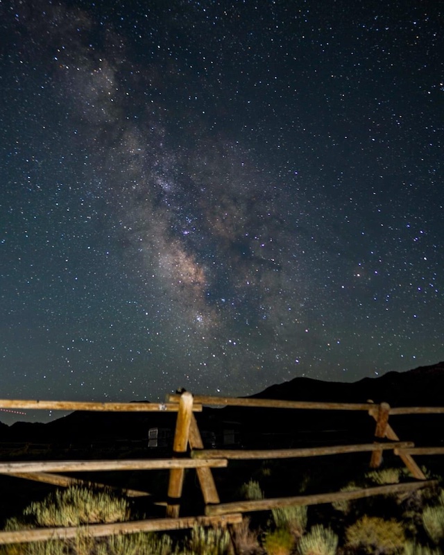 A fence line with milky way lighting up the stargazing night sky