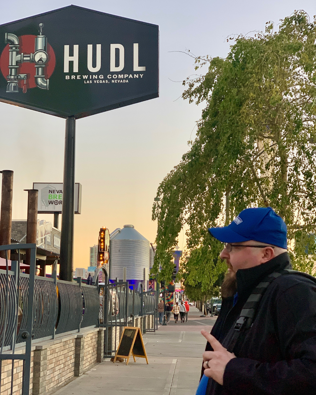 Dusk in the 18b arts district and a Brews Cruise tour guide points to the Hudl beer sign