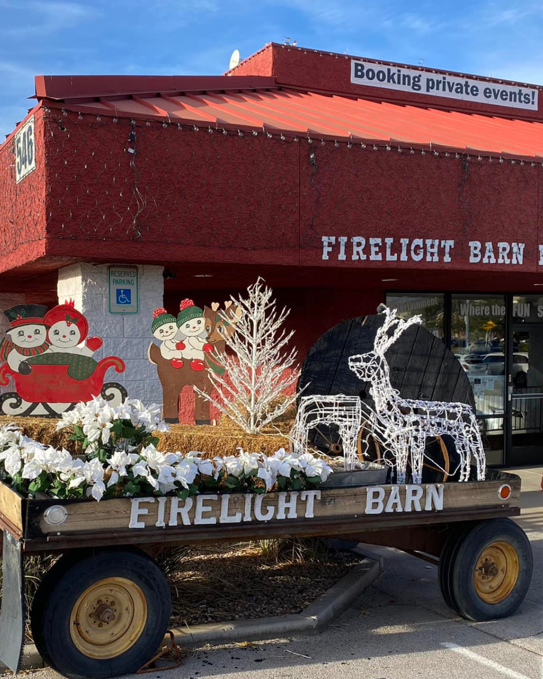 A hayride trailer with holiday decorations in front of the red roofed fire light barn