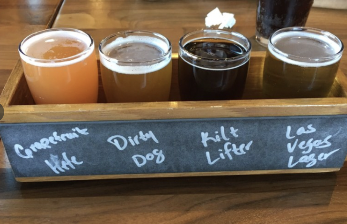 Four craft beers in a wood box with chalkboard writing.