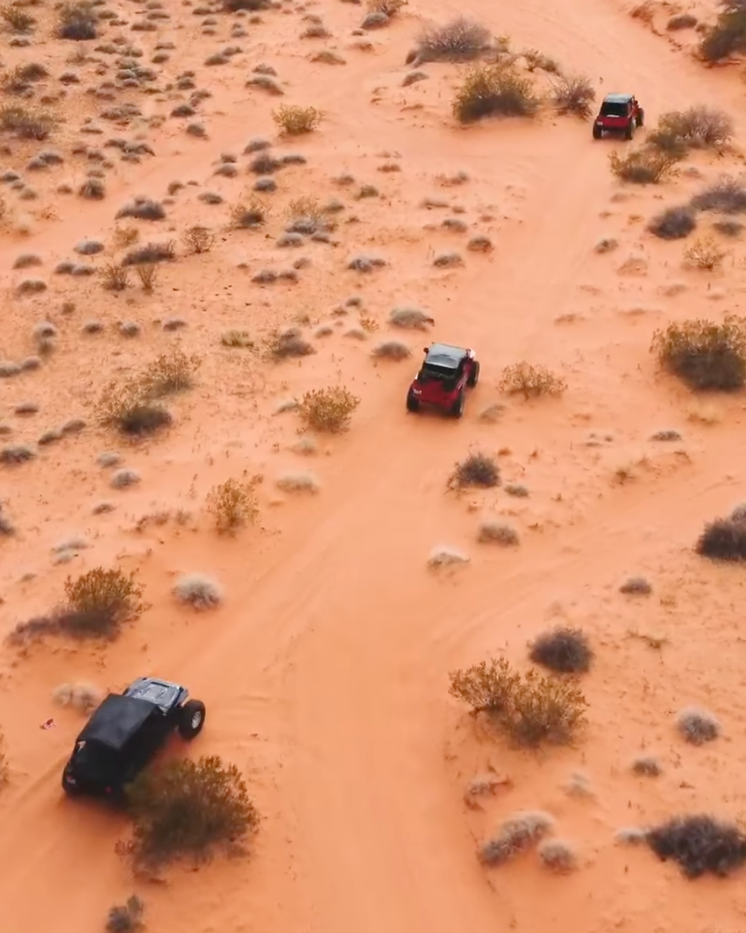 A drone shot of three jeeps driving over the sand of Valley of Fire.