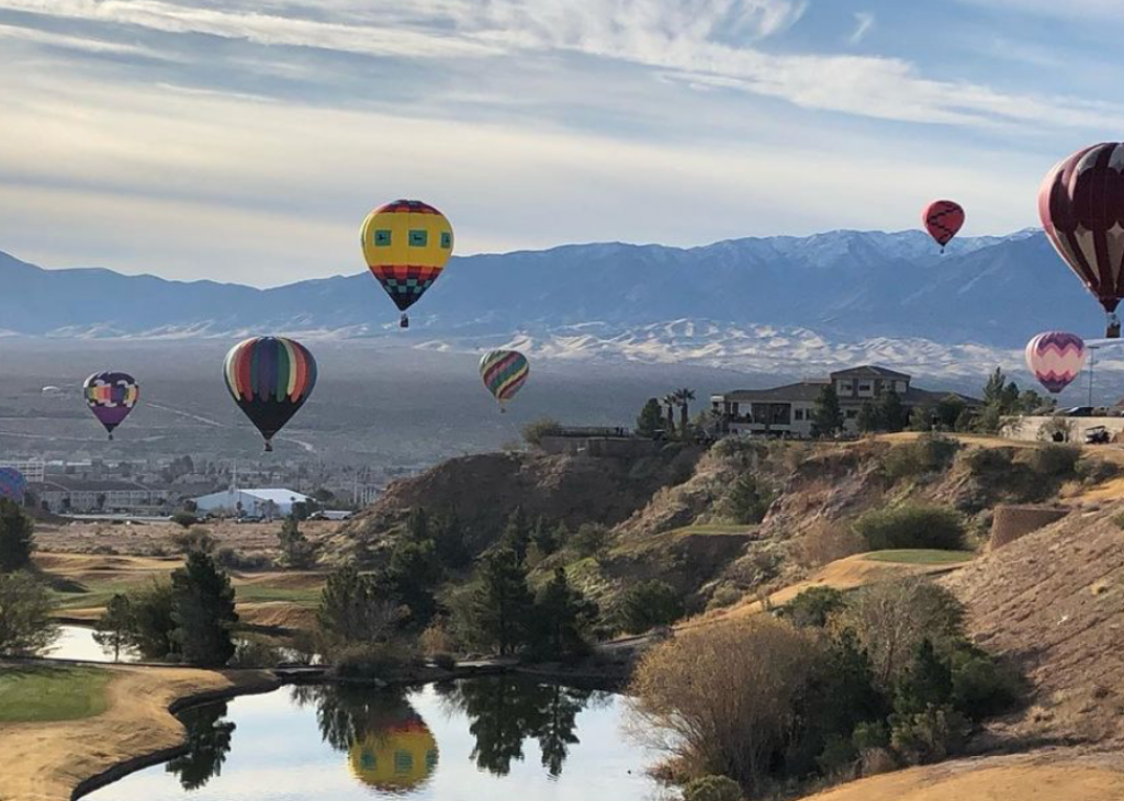 six hot air balloons floating over a Mesquite NV golf course