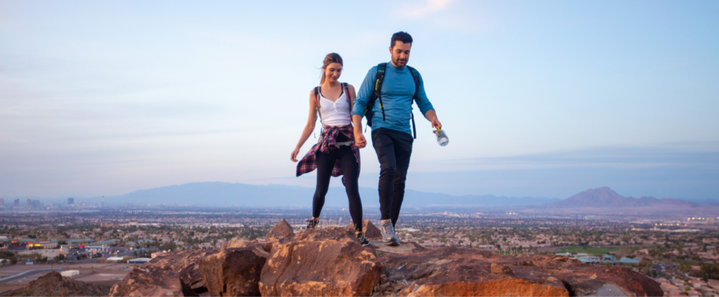 A man and woman hiking a trail in Henderson Nevada that overlooks las vegas