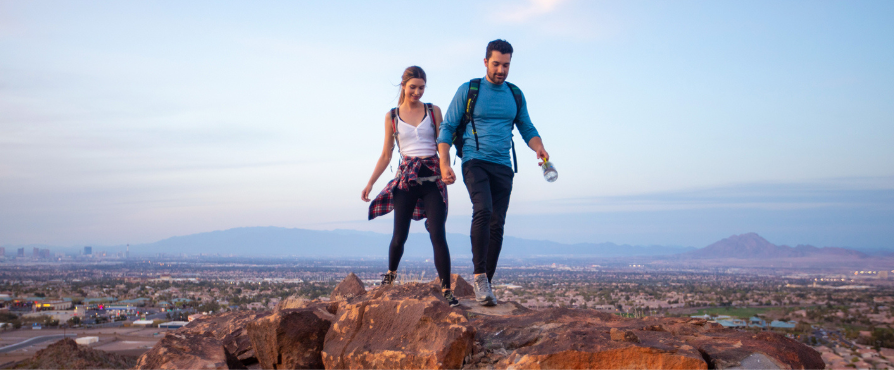 A man and woman hiking a trail in Henderson Nevada that overlooks las vegas