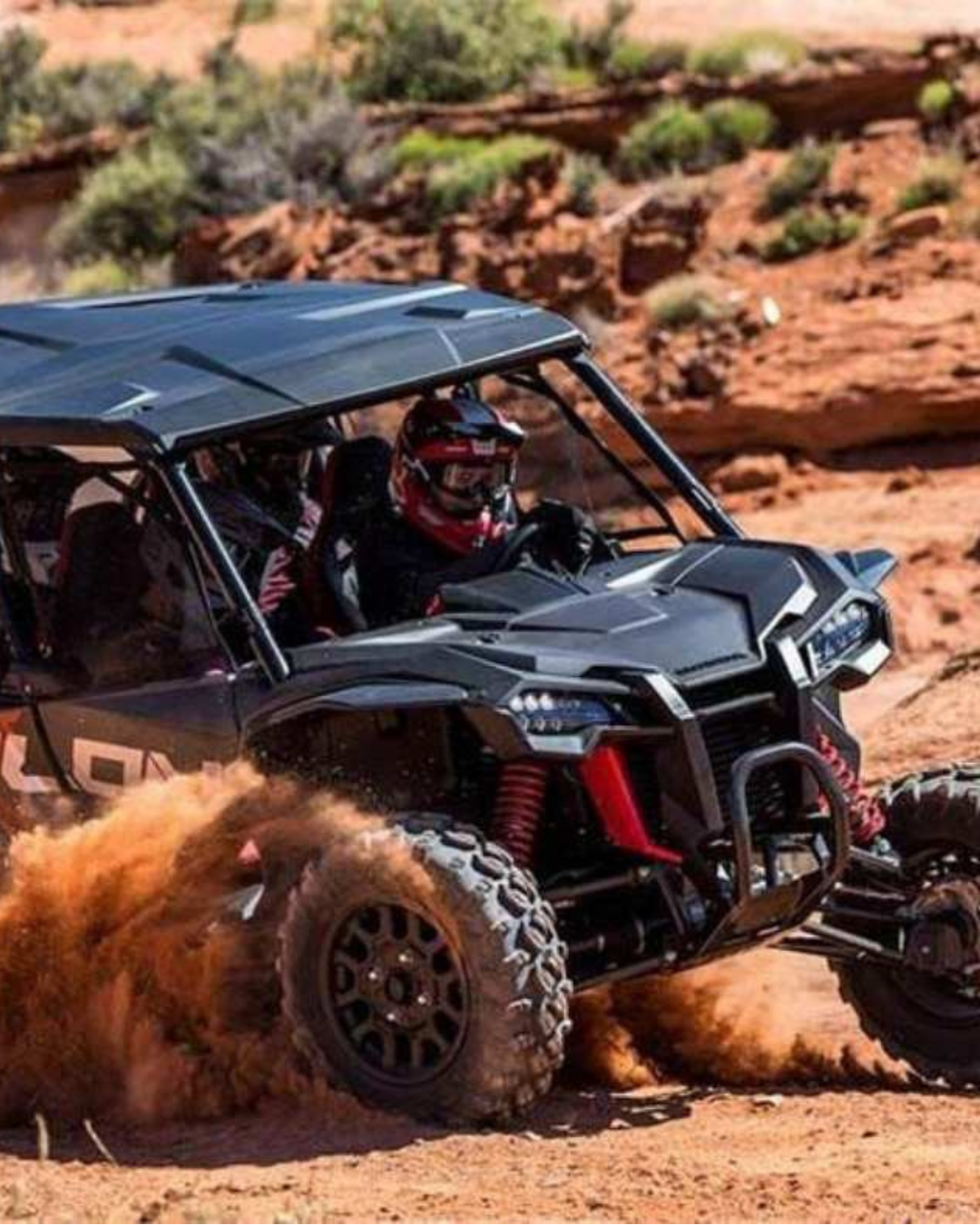 A black UTV tearing across the desert kicking up dust at Adrenaline Mountain in Goodsprings