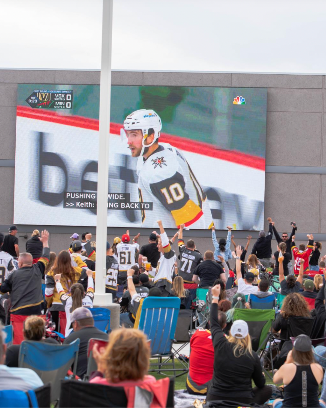 Vegas Golden Knights game on an outside screen with people cheering.