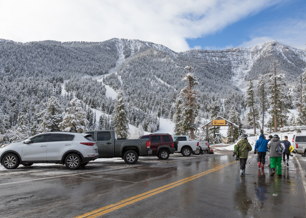 A view of the entry way to Lee Canyon slopes shows a group of people walking through the parking area to the resort.