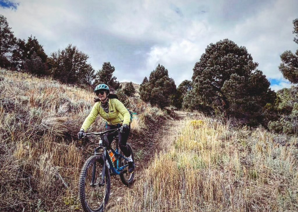 A female bicyclist treading downward on Ward Mountain in Ely.