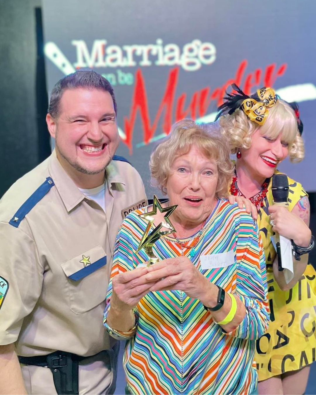 Two characters the lieutenant and hostess from Marriage Can Be Murder next to a guest who won the Super Sleuth trophy.