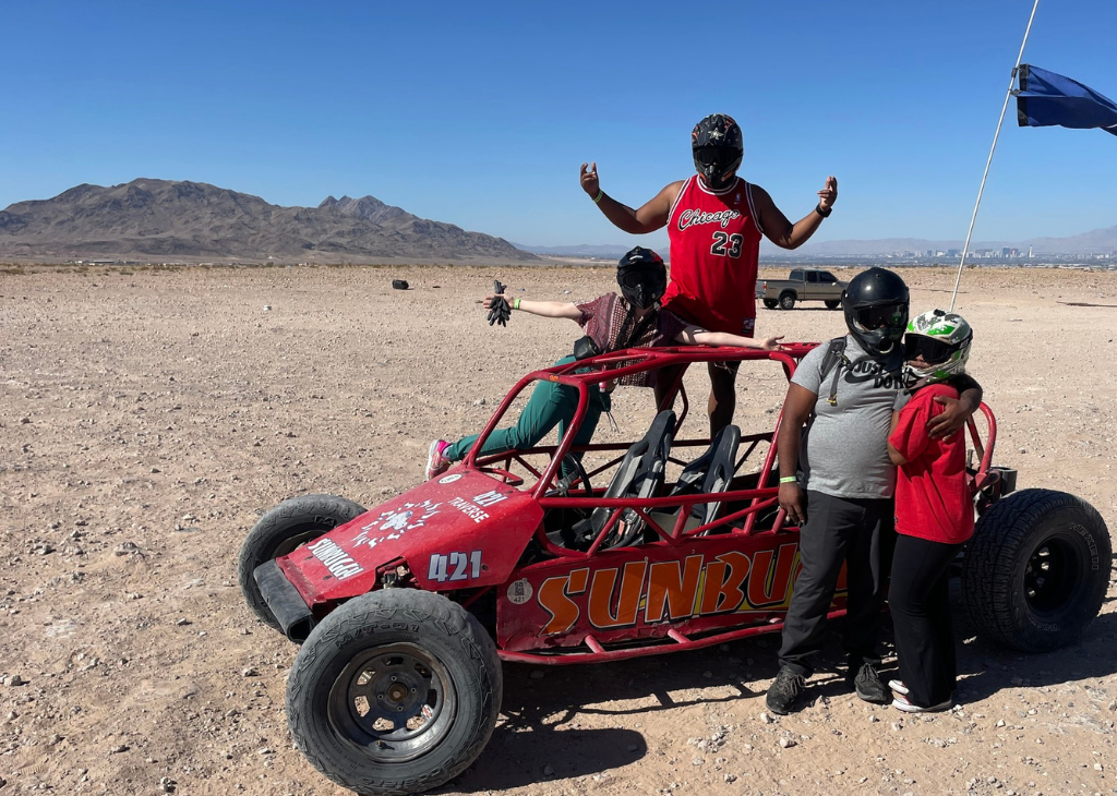 A red buggy vehicle with four people giving a merry pose. Kids ride free in December 23.