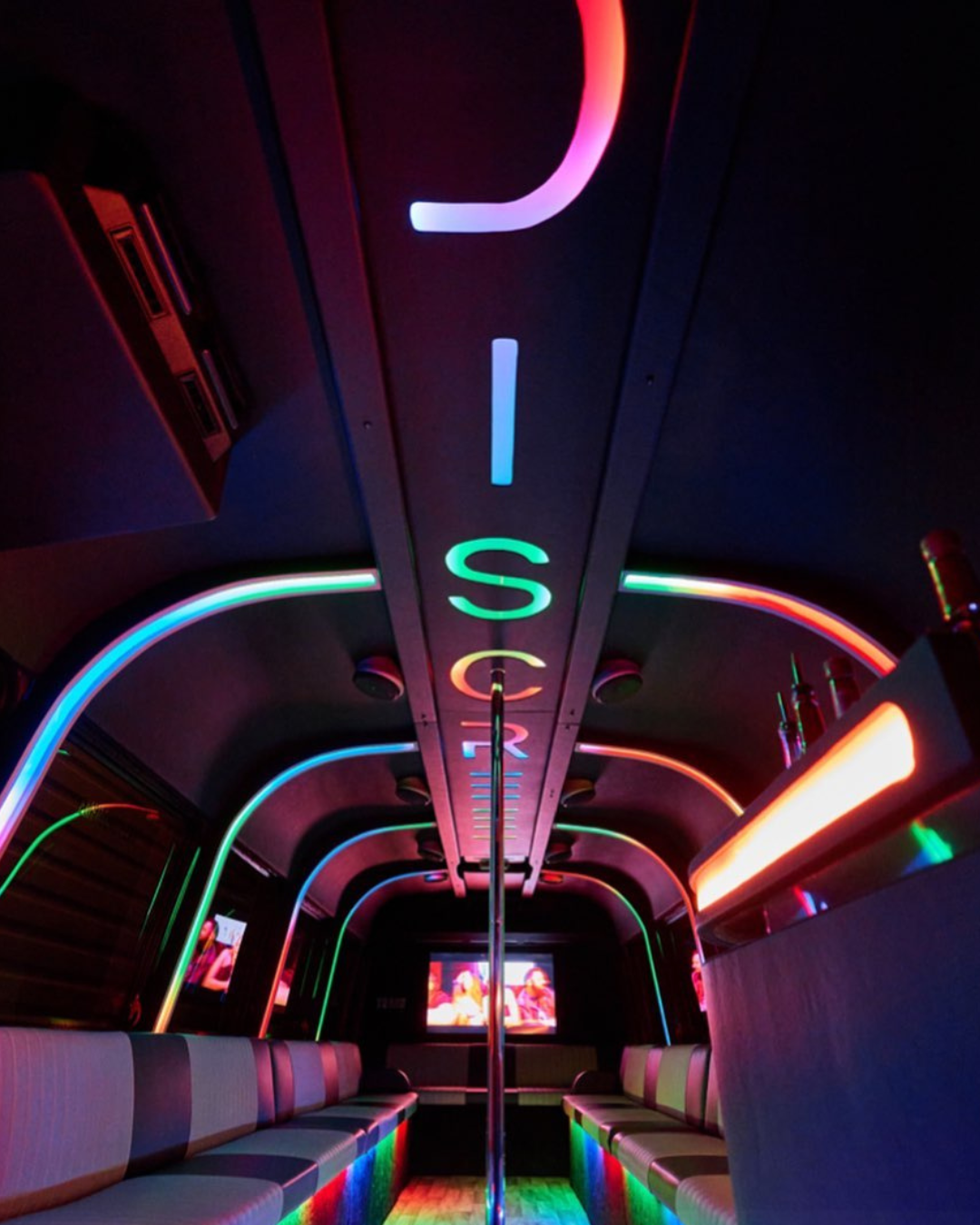 The inside of Discreet bus lit up in neon colors spelling DISCREET on the ceiling.