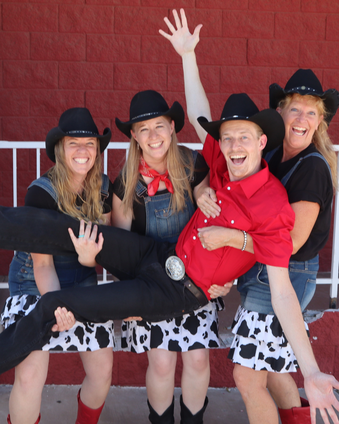 The members of mama's wranglers getting merry as the three females hold up a the male band member with his jazz hands.