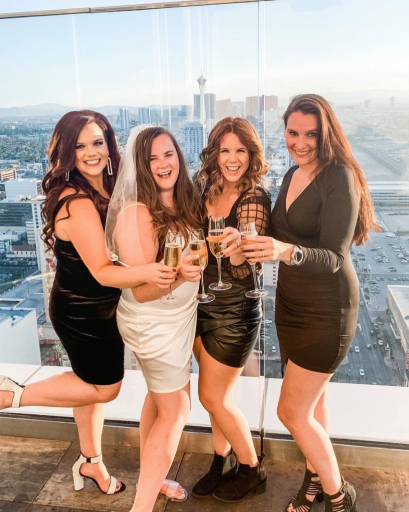 A bride and three friends toast at sunset at Legacy Club and the view is toward the north end of the Las Vegas Strip area in the distance.