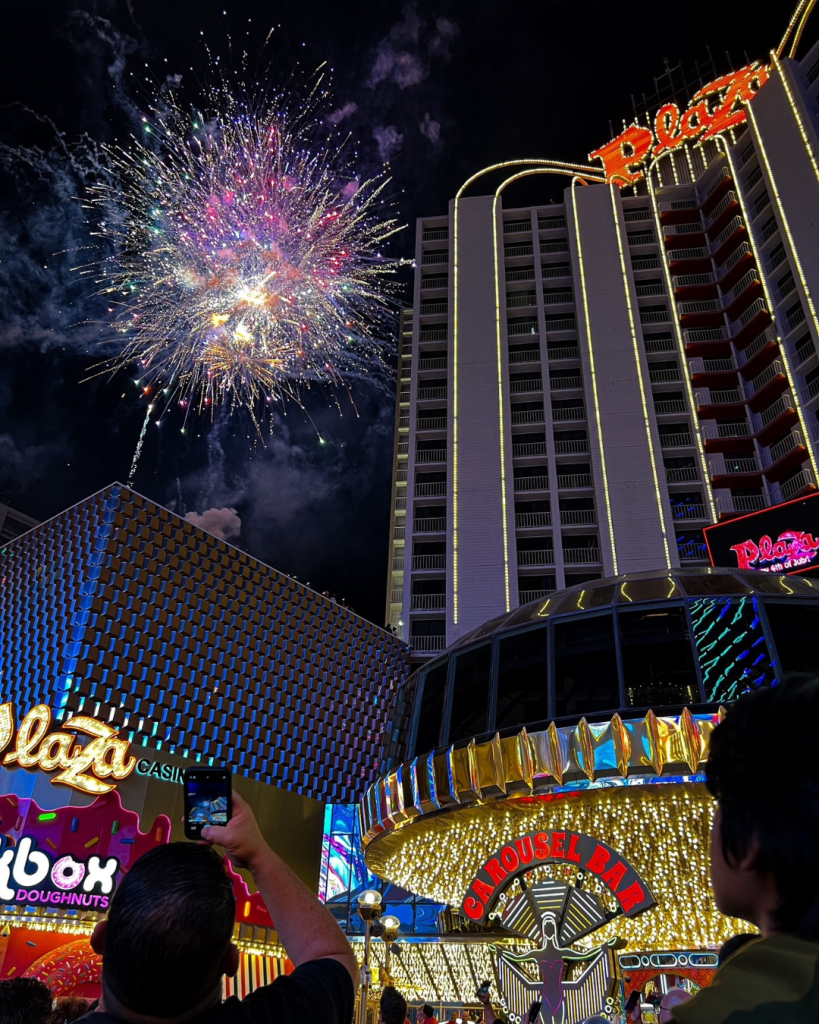 Pink white and blue fireworks going off at the Plaza the view is looking up from the hotel entry.
