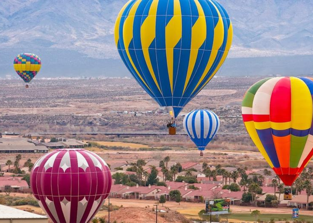 Five Hot Air Balloons flying during the morning over Mesquite with mountain backdrop at Mesquite Hot Air Balloon Festival