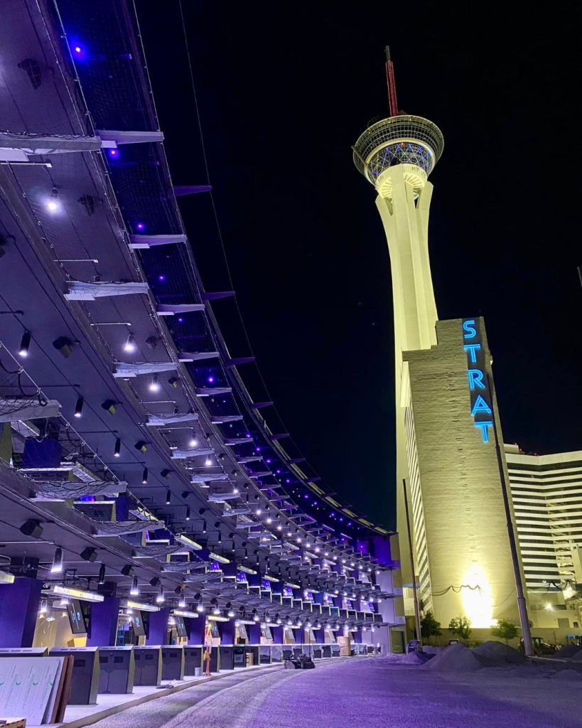Atomic Golf in Downtown Las Vegas and the golf bays are lit up all purple with the Stratosphere in the background.