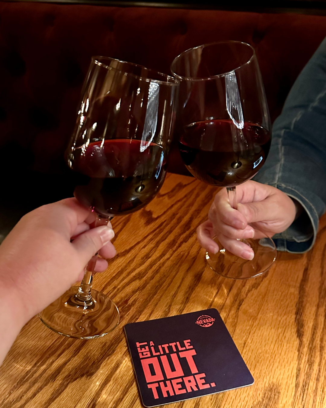 The author and friend toasting with Lady in Red Zinfindel wine, and Travel Nevada Get a Little Out There coaster.