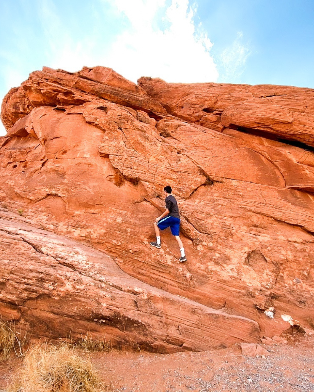 A man climbing a rock on a private tour with National Park Express at Valley of Fire in Nevada an hour outside of Las Vegas.