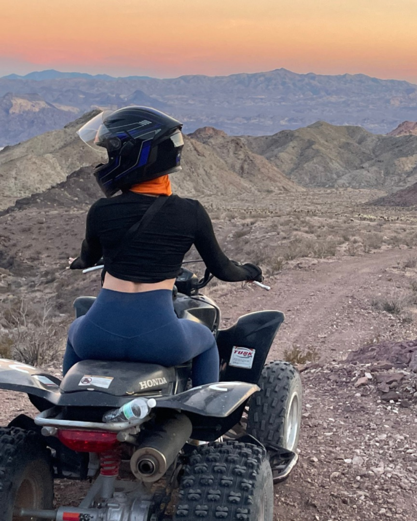A woman on an ATV watching the sunset on a tour with Awesome Adventures.