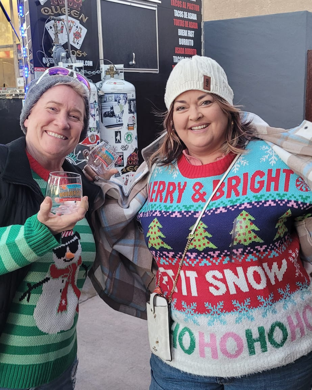 Two wine walk participants with holiday sweaters on.