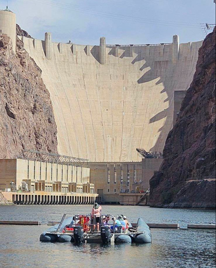People enjoy a boat ride in front of a dam at Las Vegas Territory.