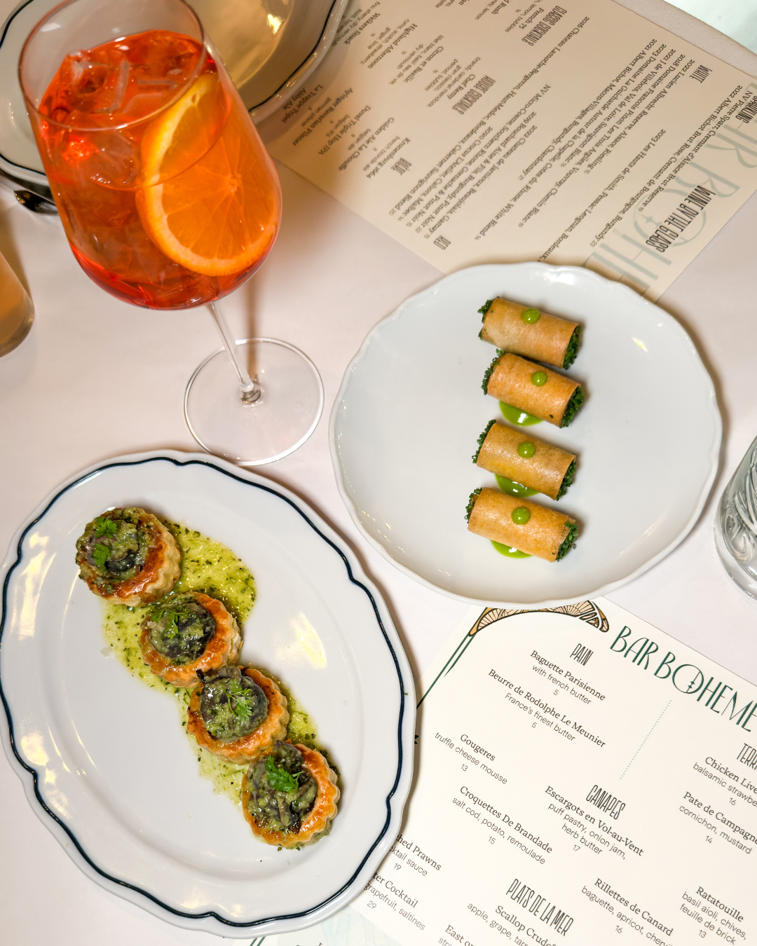 Appetizers on a plate surrounded by a Bar Boheme menu and drink. Located in the 18b Arts District in Las Vegas.