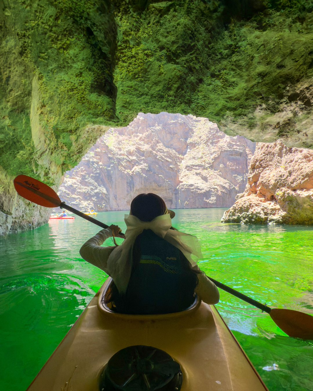 A female kayaker in Emerald Cave surround by green water. Evolution Expeditions is a tour company that can get you there.