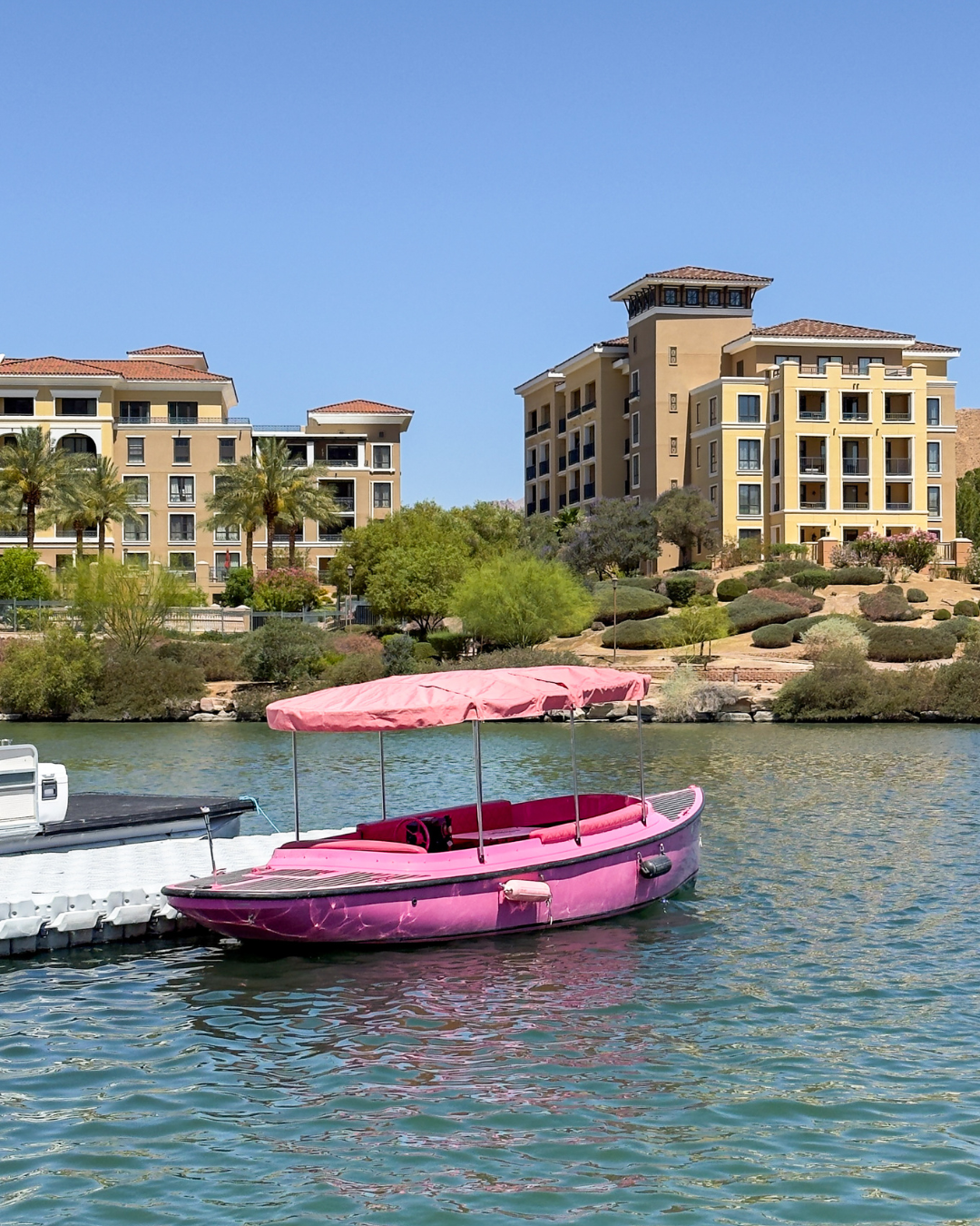A pink boat traveling across Lake Las Vegas with hotels behind. Photo Tours Las Vegas has this option in their portfolio.