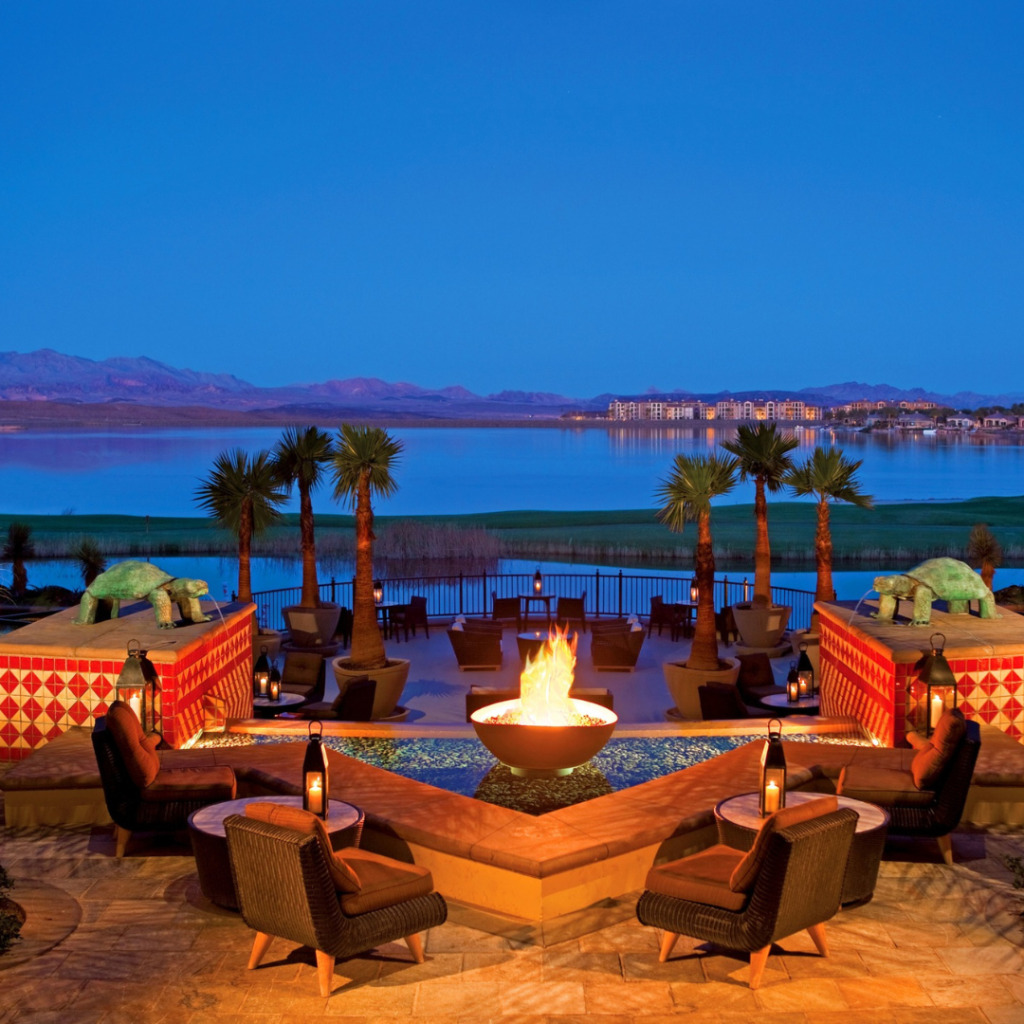 A fire pit area at a hotel at Lake Las Vega overlooking palm trees, water and mountains. This is a short drive from Henderson Nevada.