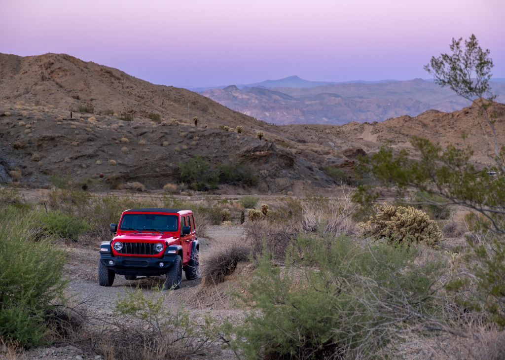 A red jeep from Vegas Jeep Tours in the desert around Nelson Nevada at dusk.